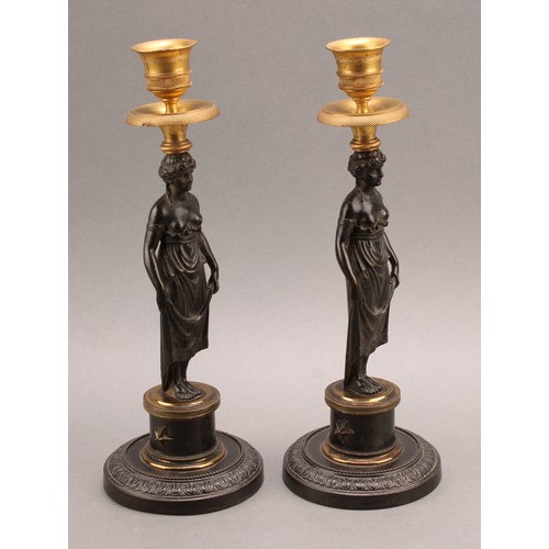 2436 - A pair of 19th century Grecian Revival parcel gilt and dark patinated bronze figural candlesticks, c... 