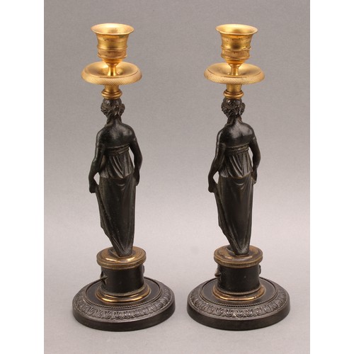 2436 - A pair of 19th century Grecian Revival parcel gilt and dark patinated bronze figural candlesticks, c... 