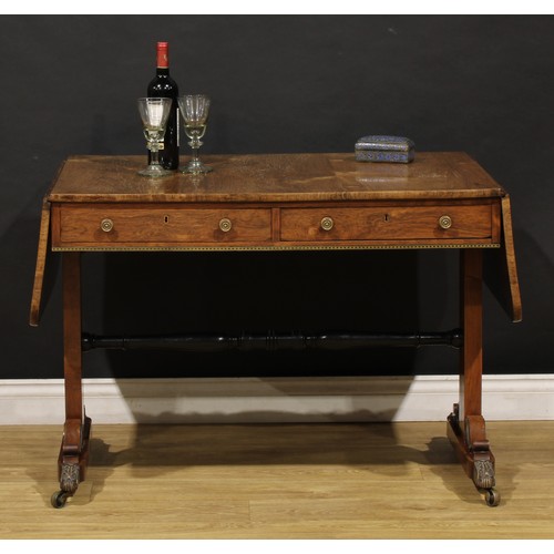 1944 - A Regency brass mounted rosewood sofa table, rounded rectangular top with fall leaves above a pair o... 