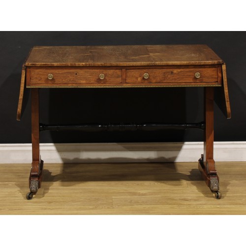 1944 - A Regency brass mounted rosewood sofa table, rounded rectangular top with fall leaves above a pair o... 