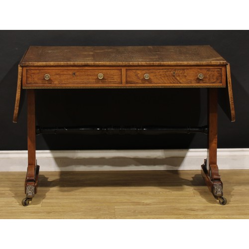 1944 - A Regency brass mounted rosewood sofa table, rounded rectangular top with fall leaves above a pair o... 