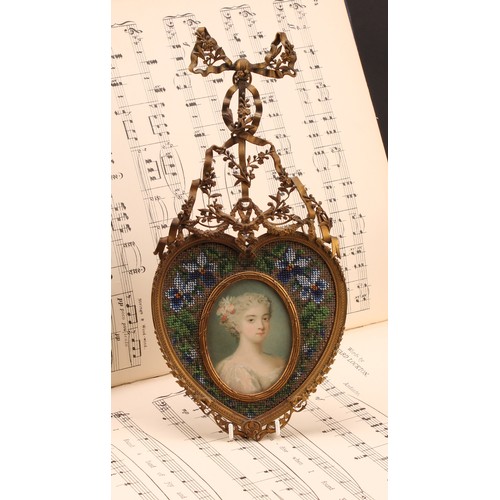 2325 - A 19th century French gilt metal and beadwork picture frame, the heart shaped frame centred by an ov... 