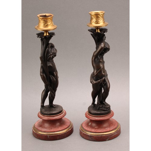 2082 - A pair of 19th century brown patinated bronze figural candlesticks, gilt sconces, turned marble base... 