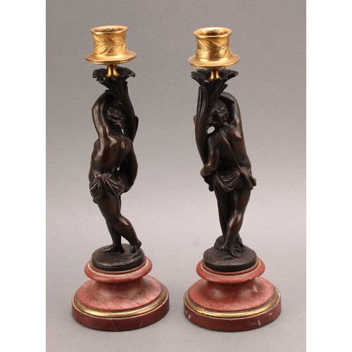 2082 - A pair of 19th century brown patinated bronze figural candlesticks, gilt sconces, turned marble base... 