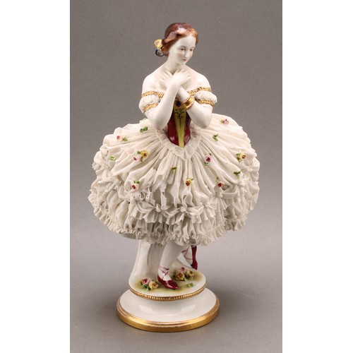 233 - A German Volkstedt porcelain figure of a ballerina, wearing a lace porcelain skirt encrusted with fl... 