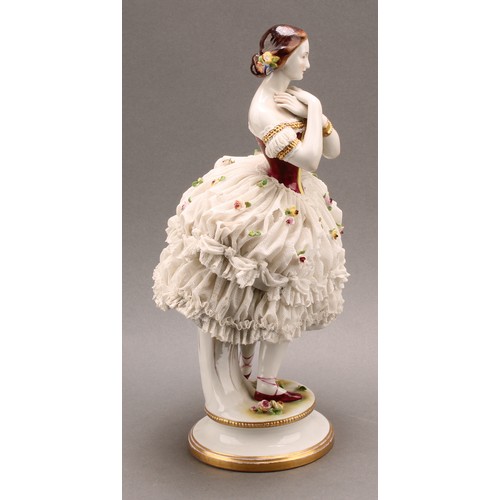 233 - A German Volkstedt porcelain figure of a ballerina, wearing a lace porcelain skirt encrusted with fl... 