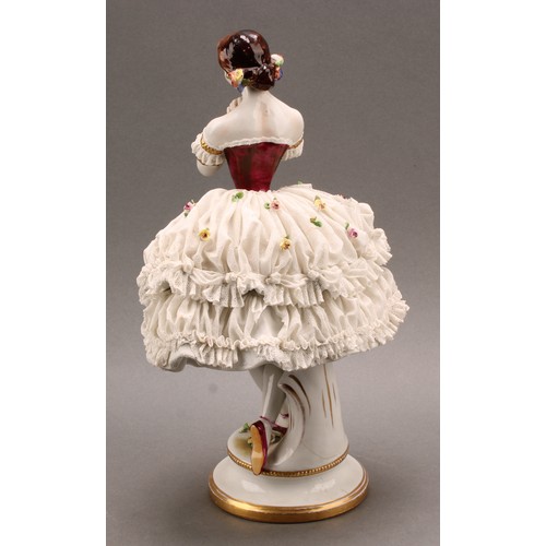 233 - A German Volkstedt porcelain figure of a ballerina, wearing a lace porcelain skirt encrusted with fl... 