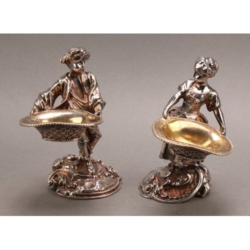 682 - A pair of Rococo Revival silver plated figural salts, cast as a fisher boy and girl holding baskets,... 