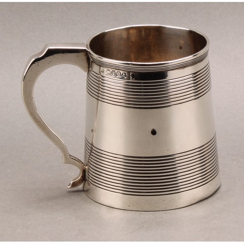 788 - A George III silver spreading cylindrical mug, moulded rim above two broad reeded bands, scroll hand... 