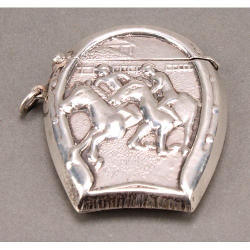 1014 - An early 20th century silver novelty vesta case, embossed with a horse racing scene within a horsesh... 