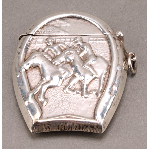 1014 - An early 20th century silver novelty vesta case, embossed with a horse racing scene within a horsesh... 