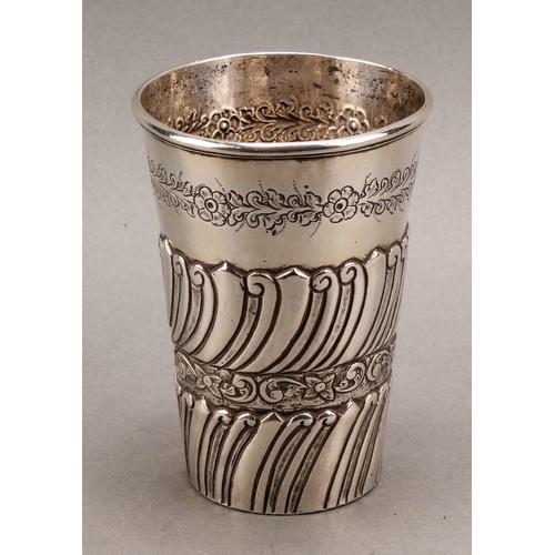 727 - A Colonial silver coloured metal tapered cylindrical beaker, probably South American, chased with ba... 