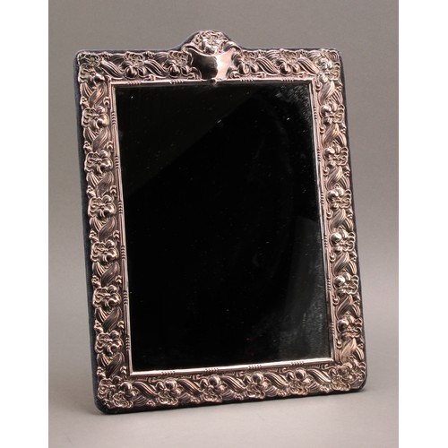 841 - A large Elizabeth II silver rectangular easel dressing table mirror, profusely embossed with flowers... 