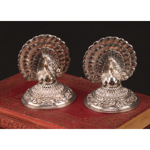 1137 - A pair of late Victorian silver plated menu holders, cast as peacocks with fanned trains, the circul... 