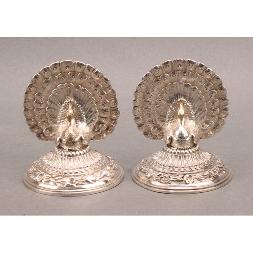 1137 - A pair of late Victorian silver plated menu holders, cast as peacocks with fanned trains, the circul... 