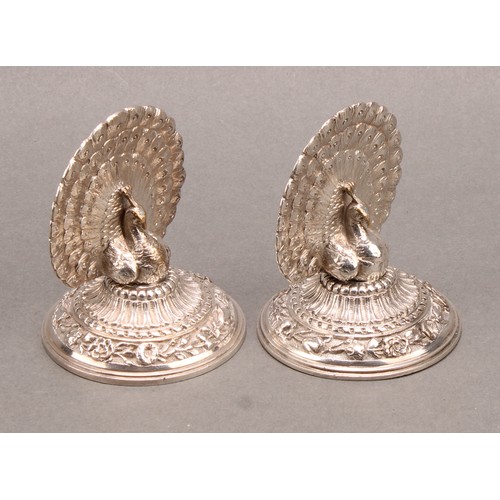 1137 - A pair of late Victorian silver plated menu holders, cast as peacocks with fanned trains, the circul... 