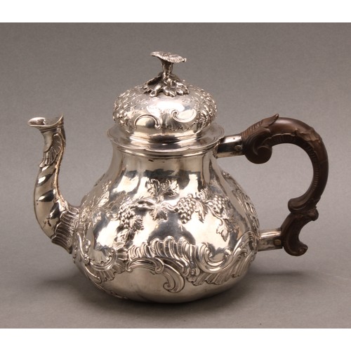 982 - An 18th century German silver pear shaped teapot, chased with fruiting vine and flowering C-scrolls,... 