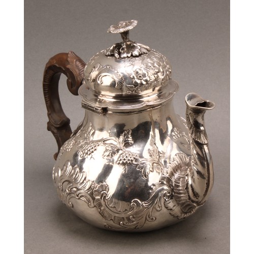 982 - An 18th century German silver pear shaped teapot, chased with fruiting vine and flowering C-scrolls,... 