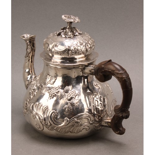 982 - An 18th century German silver pear shaped teapot, chased with fruiting vine and flowering C-scrolls,... 