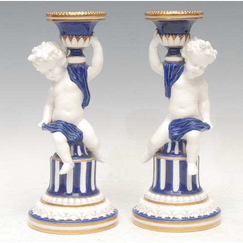 101 - A pair of Minton figural Sevres style candlesticks, campana shaped sconces, the columns with scantil... 