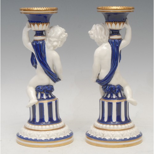 101 - A pair of Minton figural Sevres style candlesticks, campana shaped sconces, the columns with scantil... 