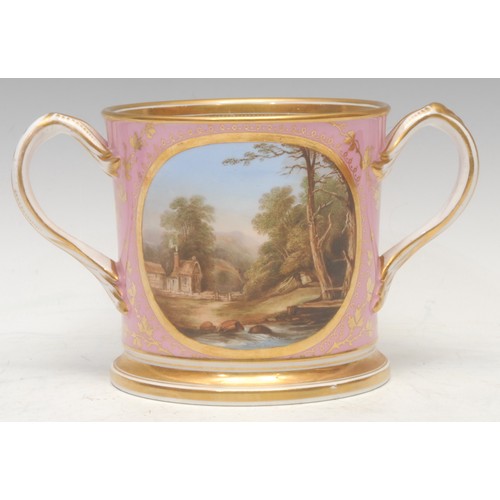 61 - A English porcelain two handled loving cup, painted with cottage by a river, within a gilt circular ... 