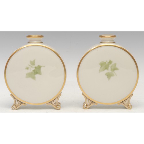 99 - A pair of Graingers Worcester pate sur pate moon flasks, decorated with leafy fronds, on a green gro... 