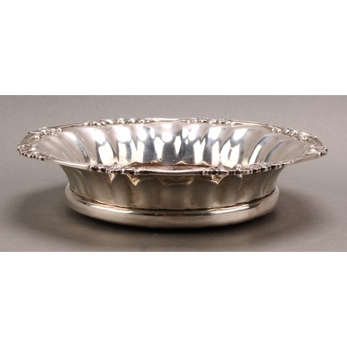 1021 - An Edwadian silver fluted circular magnum size wine coaster, of Regency design, draught-turned base,... 
