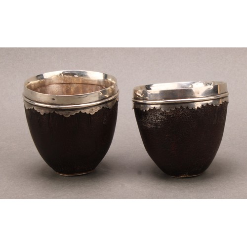 853 - A pair of 18th century silver coloured metal mounted coconut cups or tumblers, wavy pendant borders,... 