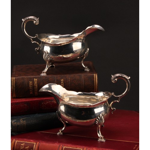 858 - A pair of early George III silver sauce boats, acanthus-capped flying scroll handles, hoof feet with... 