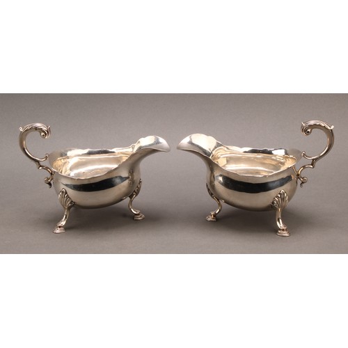 858 - A pair of early George III silver sauce boats, acanthus-capped flying scroll handles, hoof feet with... 