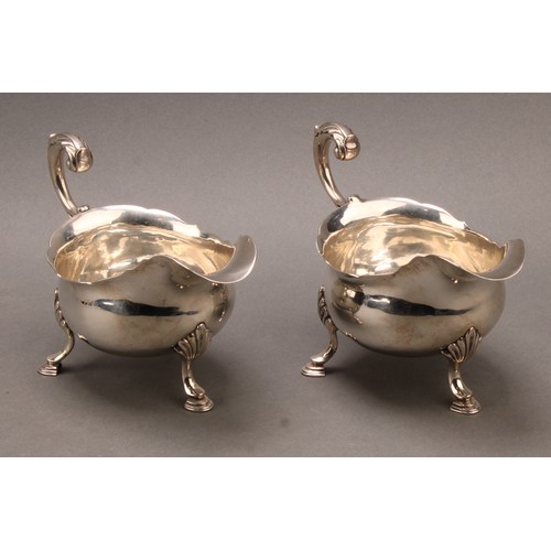 858 - A pair of early George III silver sauce boats, acanthus-capped flying scroll handles, hoof feet with... 