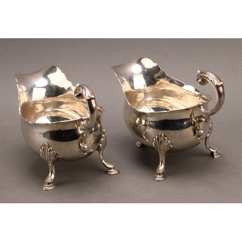 858 - A pair of early George III silver sauce boats, acanthus-capped flying scroll handles, hoof feet with... 