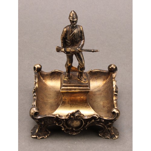 1047 - An Edwardian silver-gilt dish, of military interest, centred by a figure of a soldier from the South... 