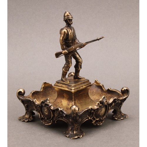 1047 - An Edwardian silver-gilt dish, of military interest, centred by a figure of a soldier from the South... 