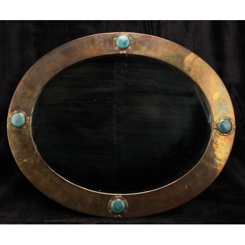 2571 - An Arts & Crafts sheet brass and simulated ‘Ruskin stone’ mounted oval looking glass, plain mirror p... 