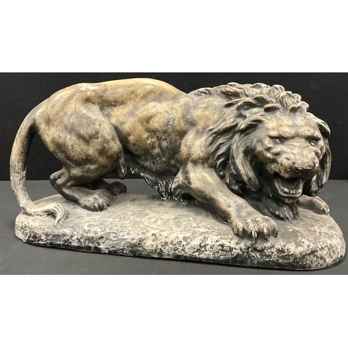 27 - A 20th century plaster model of a young male lion, braced to flee or fight, 43cm long.