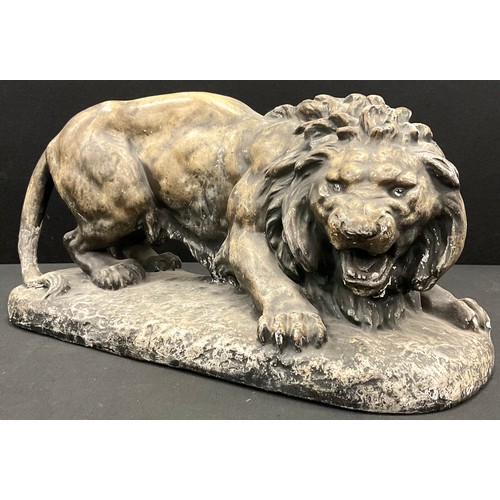 27 - A 20th century plaster model of a young male lion, braced to flee or fight, 43cm long.