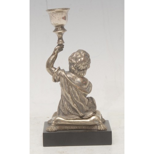 3025 - A 19th century silvered bronze figural taperstick, as a child seated on a cushion, rectangular black... 