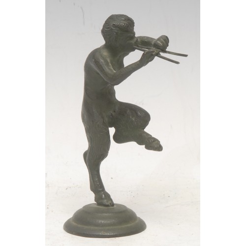3558 - A patinated bronze, of a Pan, he stands with one leg raised, playing pipes, circular base, 12cm high