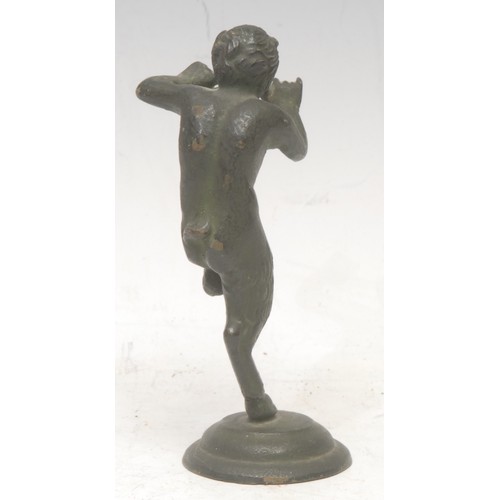 3558 - A patinated bronze, of a Pan, he stands with one leg raised, playing pipes, circular base, 12cm high