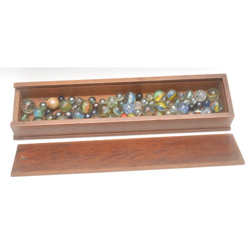 3063 - A collection of 19th century and later marbles, the mahogany box with sliding cover, 42.5cm wide