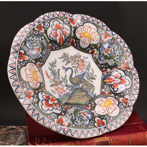 159 - A Delft lobed circular dish, painted in polychrome, with a peacock in a garden setting, the rim with... 