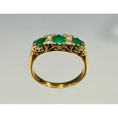 6272 - An emerald and diamond ring, three graduated mid green emeralds divided by pairs of round brilliant ... 