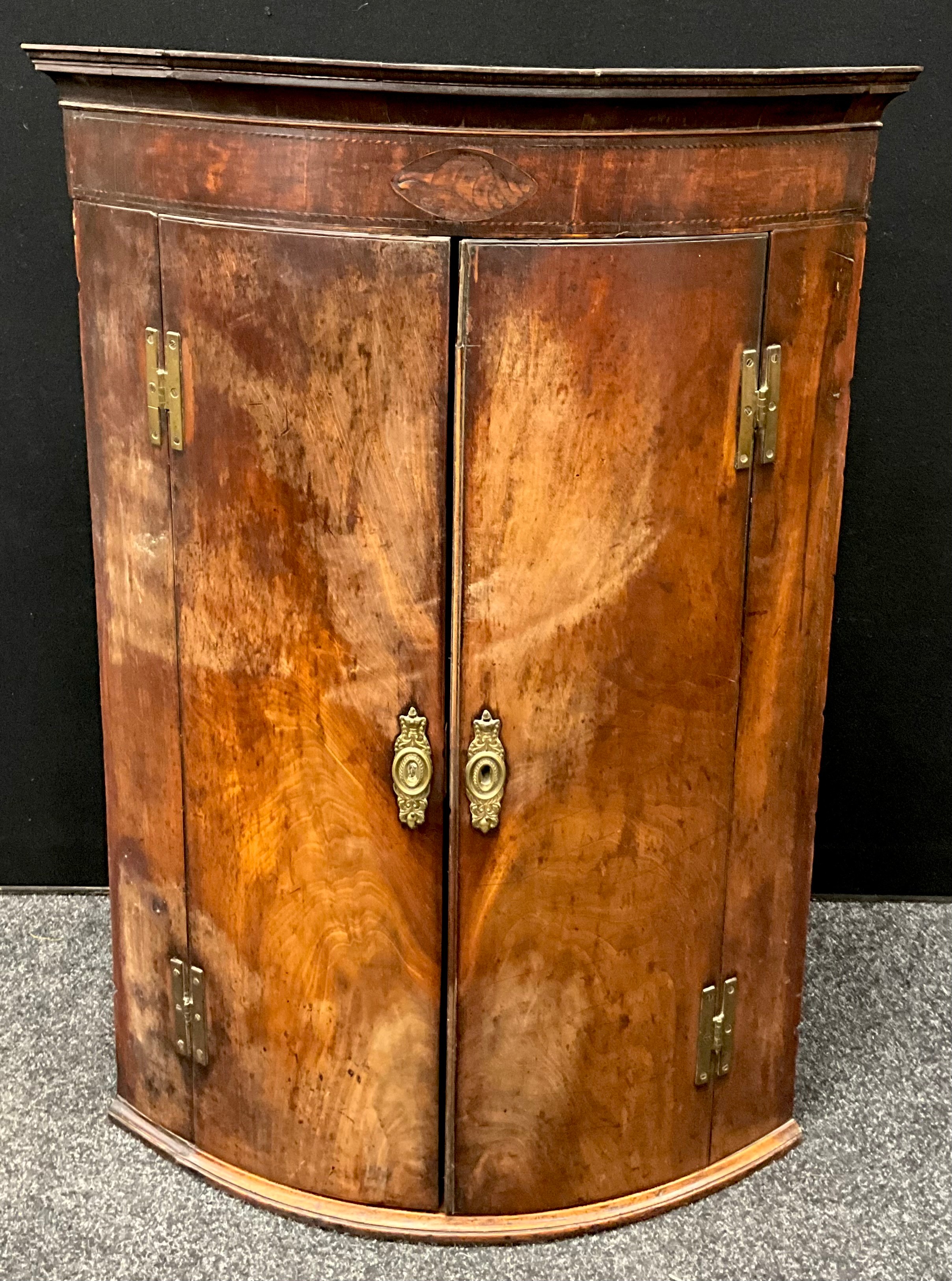 A George III mahogany bow-front corner cupboard, inlaid shell patera to ...