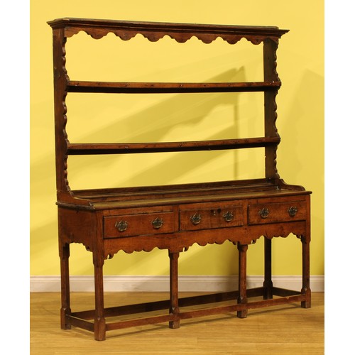 A George III oak dresser, moulded cornice above two plate rack shelves ...