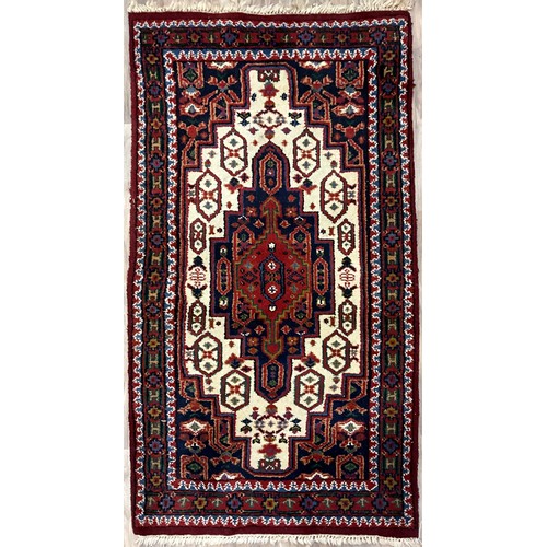 A Hand-knotted middle-eastern style woollen rug, knotted in tones of ...
