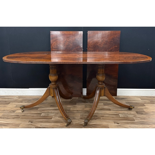 109 - A Regency style mahogany twin pedestal dining table, rounded rectangular top with a reeded edge, sup... 