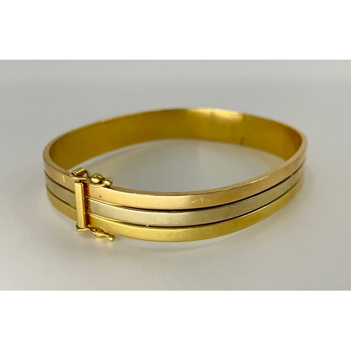 336 - An 18ct gold tri-coloured gold half hinged bangle, 
approx. 9mm max width, stamped 