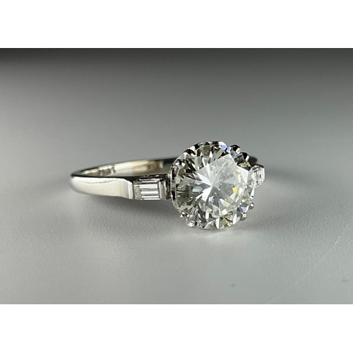 140 - A platinum solitaire diamond ring, with diamond set shoulders, set with an approx. 1.65ct round bril... 